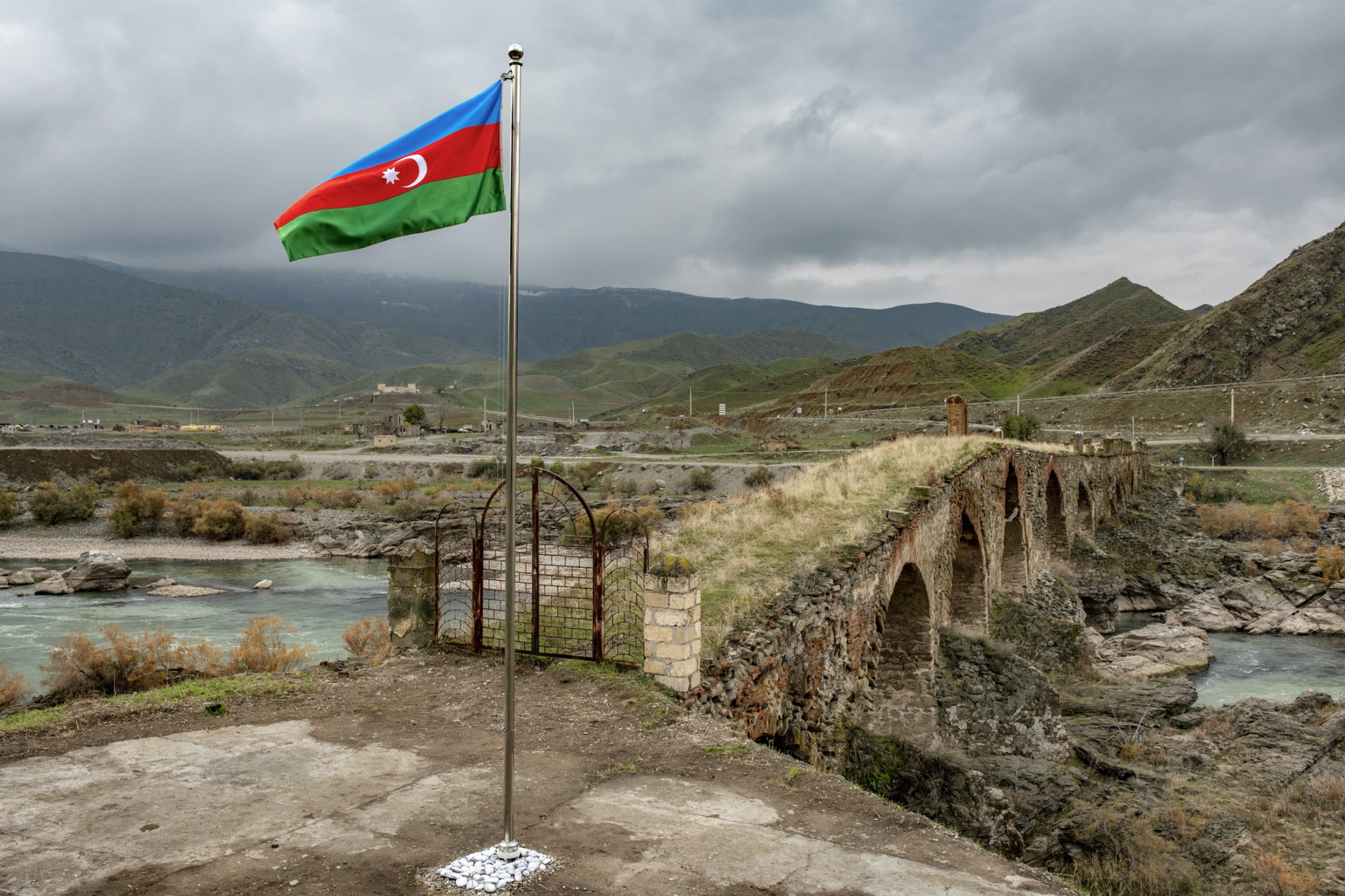 An Azeri national flag flies next to the mediaeval Khudaferin bridge in Jebrayil district at the country_s border with Iran on 9 December 2020 (AFP)