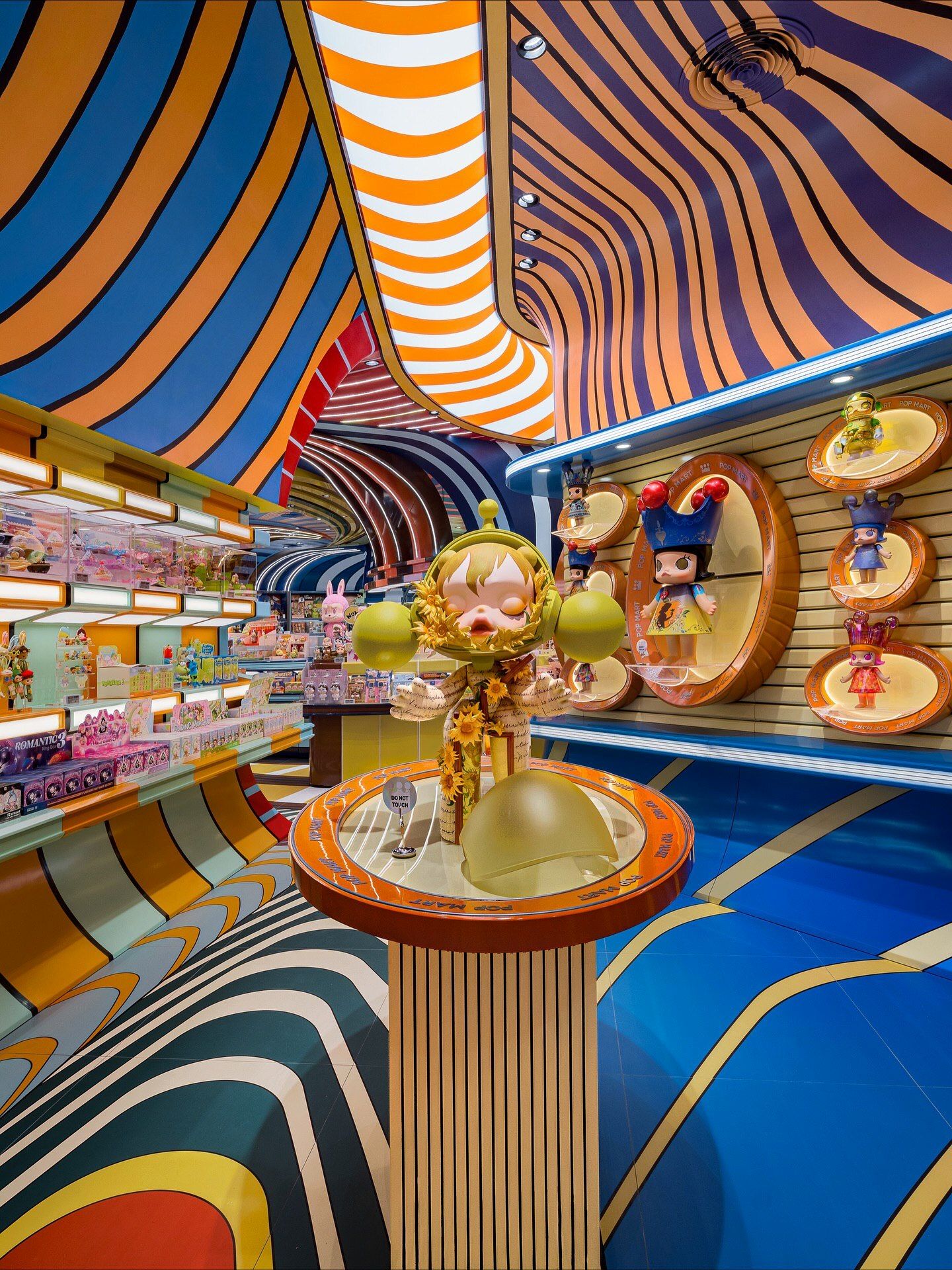 تصاویری از فضای داخلی فروشگاه پرچمدار برند پاپ مارت (POP MART) در مرکز خرید آیکون سیام بانکوک، که توسط استودیوی X+Living با طراحی مفهومی و الهام از نقوش معبد وات آرون تایلند اجرا شده و دارای فضای پیکسلی و کافه «داستان پریان» است.