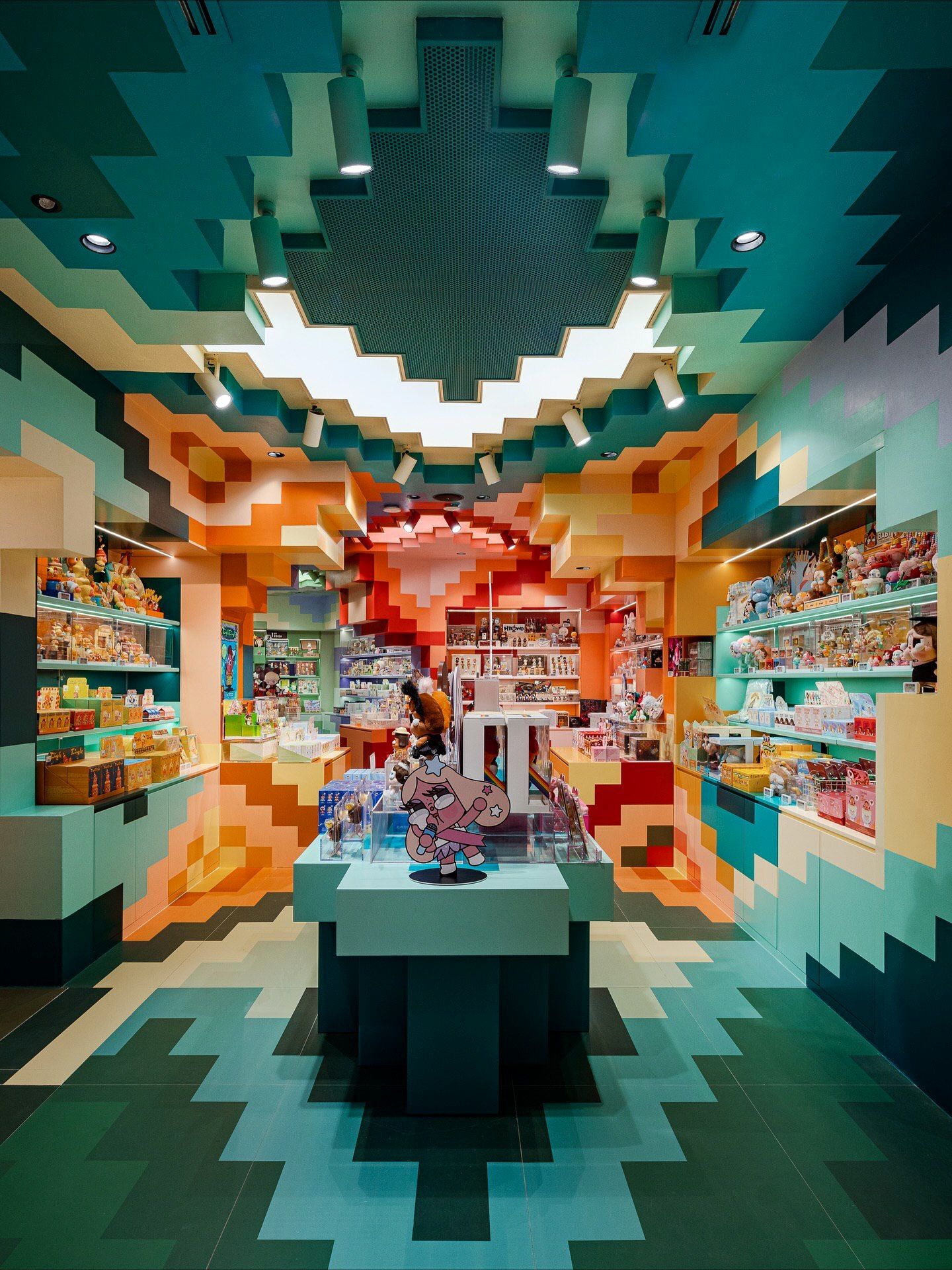 تصاویری از فضای داخلی فروشگاه پرچمدار برند پاپ مارت (POP MART) در مرکز خرید آیکون سیام بانکوک، که توسط استودیوی X+Living با طراحی مفهومی و الهام از نقوش معبد وات آرون تایلند اجرا شده و دارای فضای پیکسلی و کافه «داستان پریان» است.