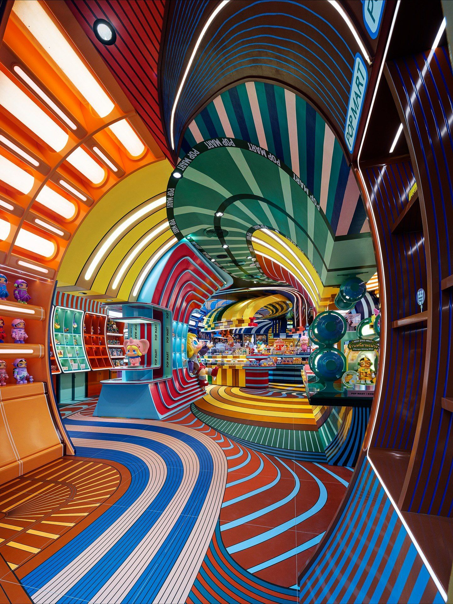 تصاویری از فضای داخلی فروشگاه پرچمدار برند پاپ مارت (POP MART) در مرکز خرید آیکون سیام بانکوک، که توسط استودیوی X+Living با طراحی مفهومی و الهام از نقوش معبد وات آرون تایلند اجرا شده و دارای فضای پیکسلی و کافه «داستان پریان» است.