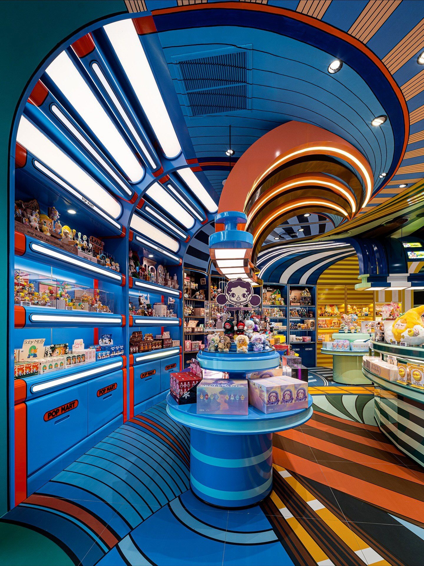 تصاویری از فضای داخلی فروشگاه پرچمدار برند پاپ مارت (POP MART) در مرکز خرید آیکون سیام بانکوک، که توسط استودیوی X+Living با طراحی مفهومی و الهام از نقوش معبد وات آرون تایلند اجرا شده و دارای فضای پیکسلی و کافه «داستان پریان» است.