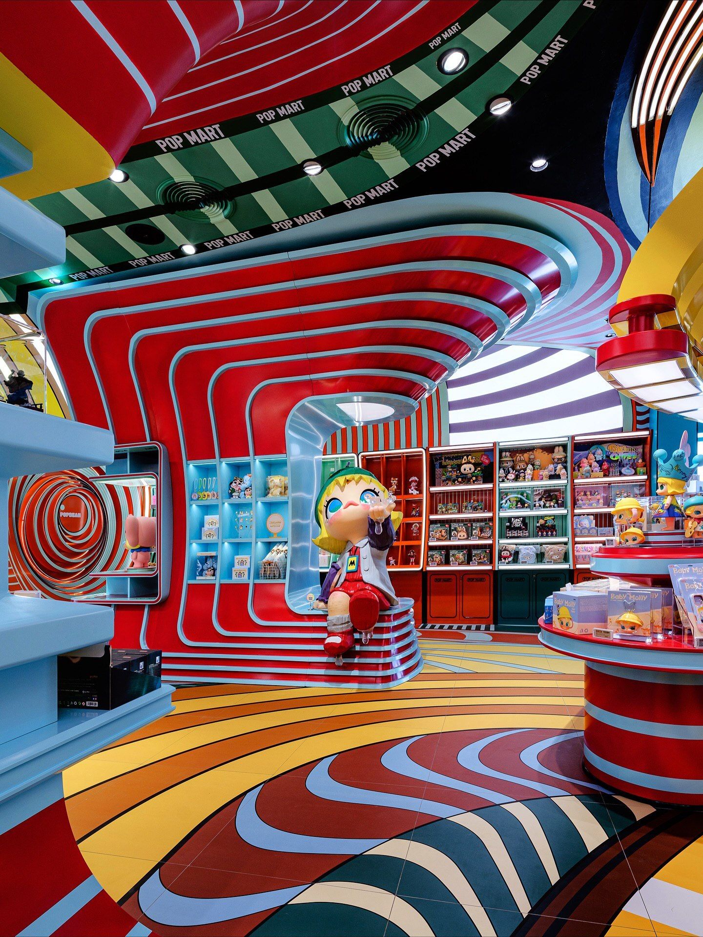 تصاویری از فضای داخلی فروشگاه پرچمدار برند پاپ مارت (POP MART) در مرکز خرید آیکون سیام بانکوک، که توسط استودیوی X+Living با طراحی مفهومی و الهام از نقوش معبد وات آرون تایلند اجرا شده و دارای فضای پیکسلی و کافه «داستان پریان» است.