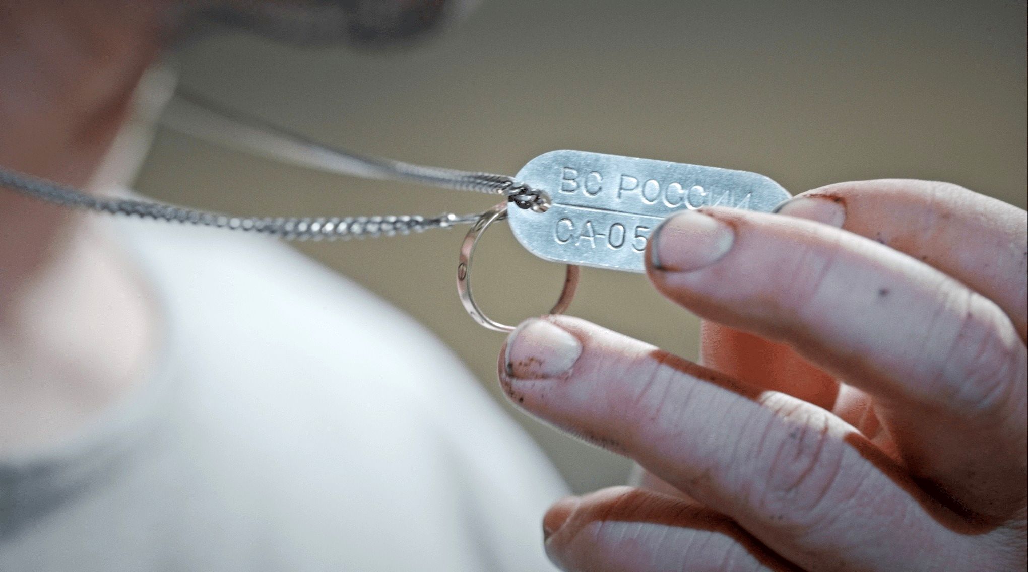 آرش دربندی یک پلاک فلزی شناسایی را در دست دارد که روی آن به زبان روسی عبارت «نیروهای مسلح روسیه» حک شده است.