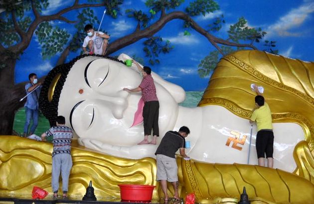کارگران در پی ویروس کرونا در بوگور  اندونزی ، پیش از جشن سال نو میلادی در چین ، یک مجسمه غول پیکر بودا را در معبدی تمیز می کنند. 